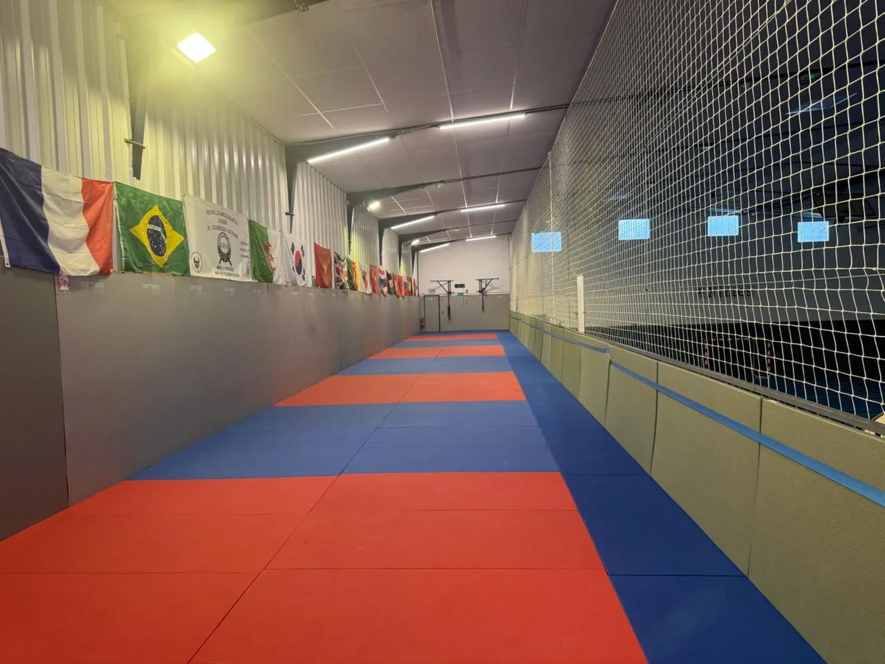 Les 185 m² de tatamis rouges et bleus de la Bouguetaia Academy à Nîmes, avec les drapeaux accrochés aux murs