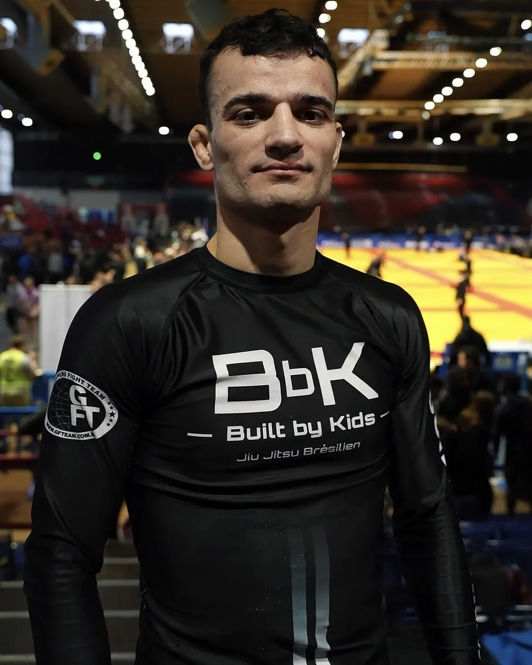 Compétiteur de Built by Kids en rashguard noir floqué Built by Kids Jiu Jitsu Brésilien et patch GFTeam, au bord des tatamis de compétition