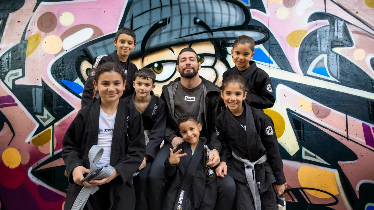 Achraf Elhazime entouré des kids du Linao Club devant la fresque graffiti