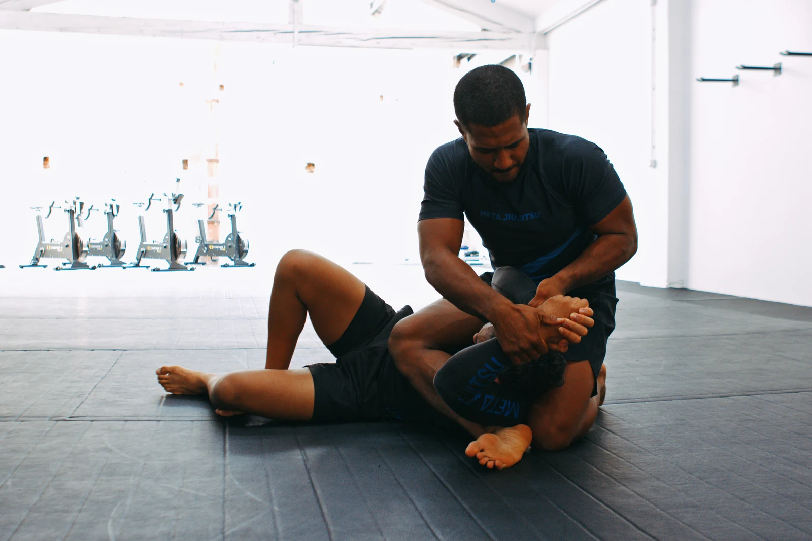 Un enseignant de Meta Jiu Jitsu travaille une technique au sol avec un élève