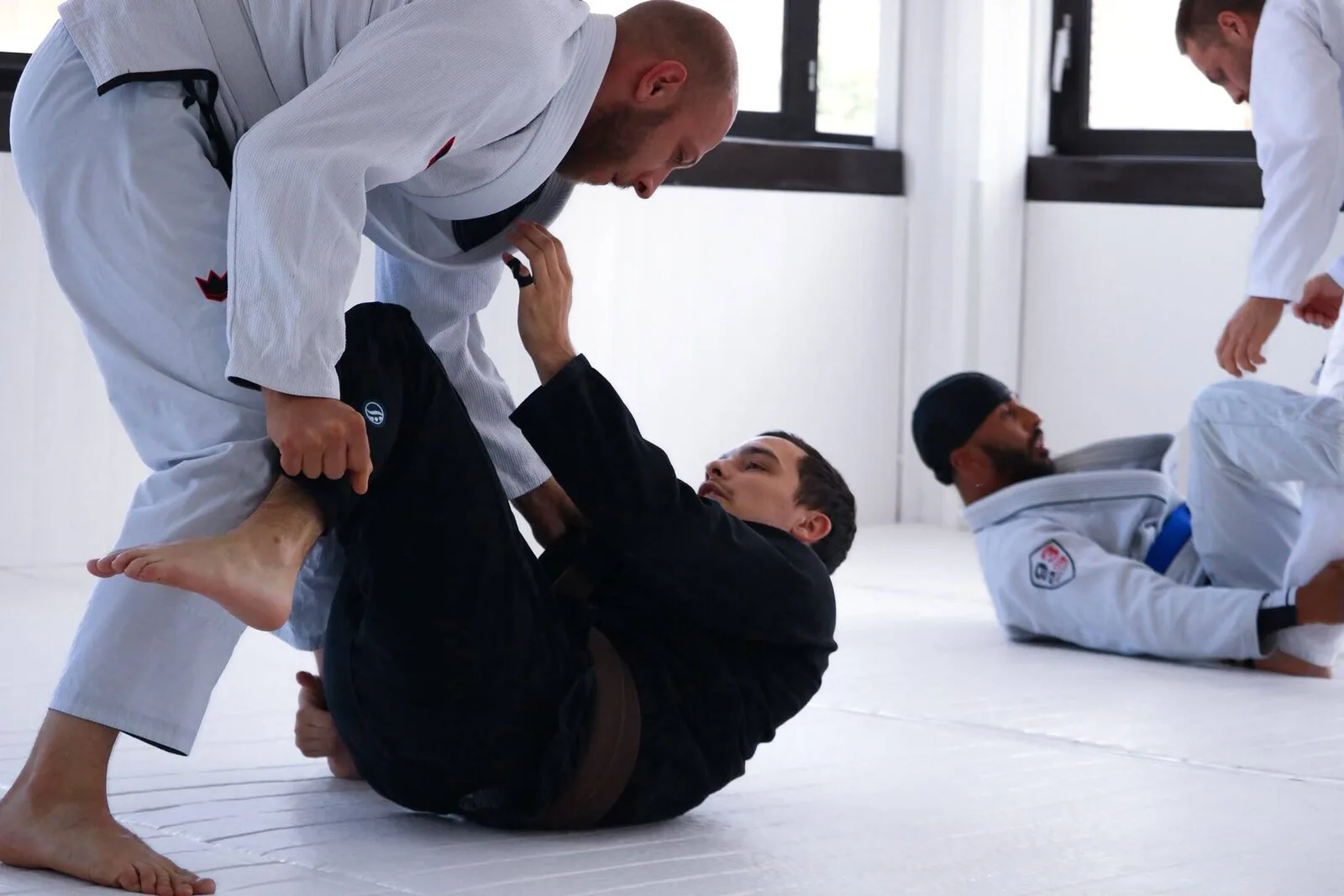 Pratiquants d'Overall Jiu-Jitsu en gi pendant un cours de jiu-jitsu brésilien sur les tatamis du club à Dijon